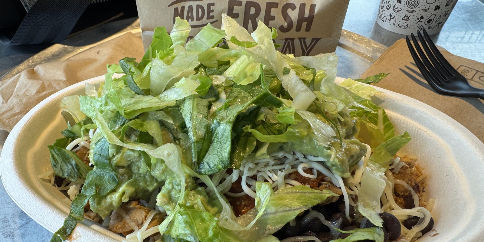 A burrito bowl with rice, beans, meat, salsa and guacamole