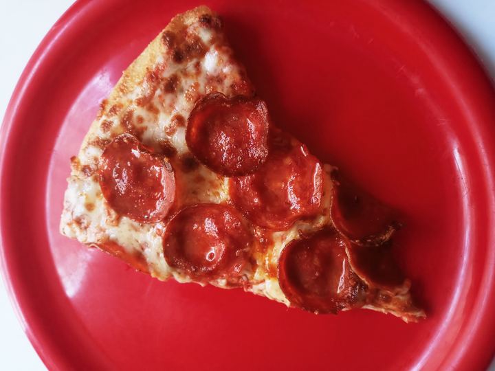 A slice of pepperoni pizza on a red plate