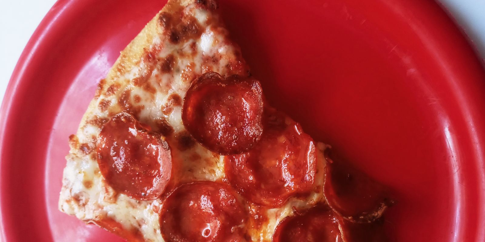 A slice of pepperoni pizza on a red plate
