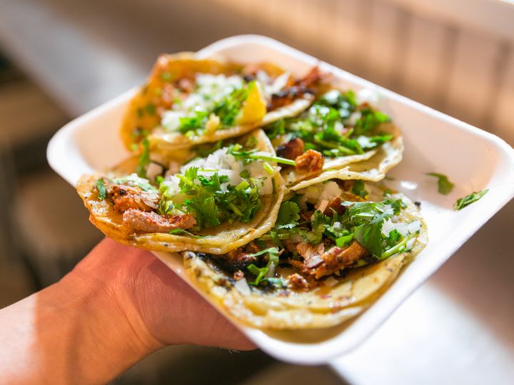 Three tacos al pastor topped with pineapple, onion and coriander
